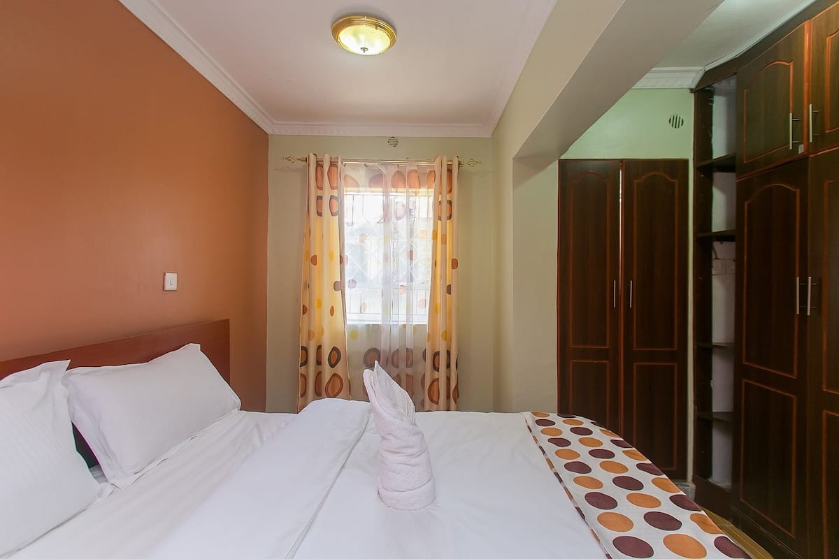 Una habitación de hotel con cama, cortinas y armario de madera.