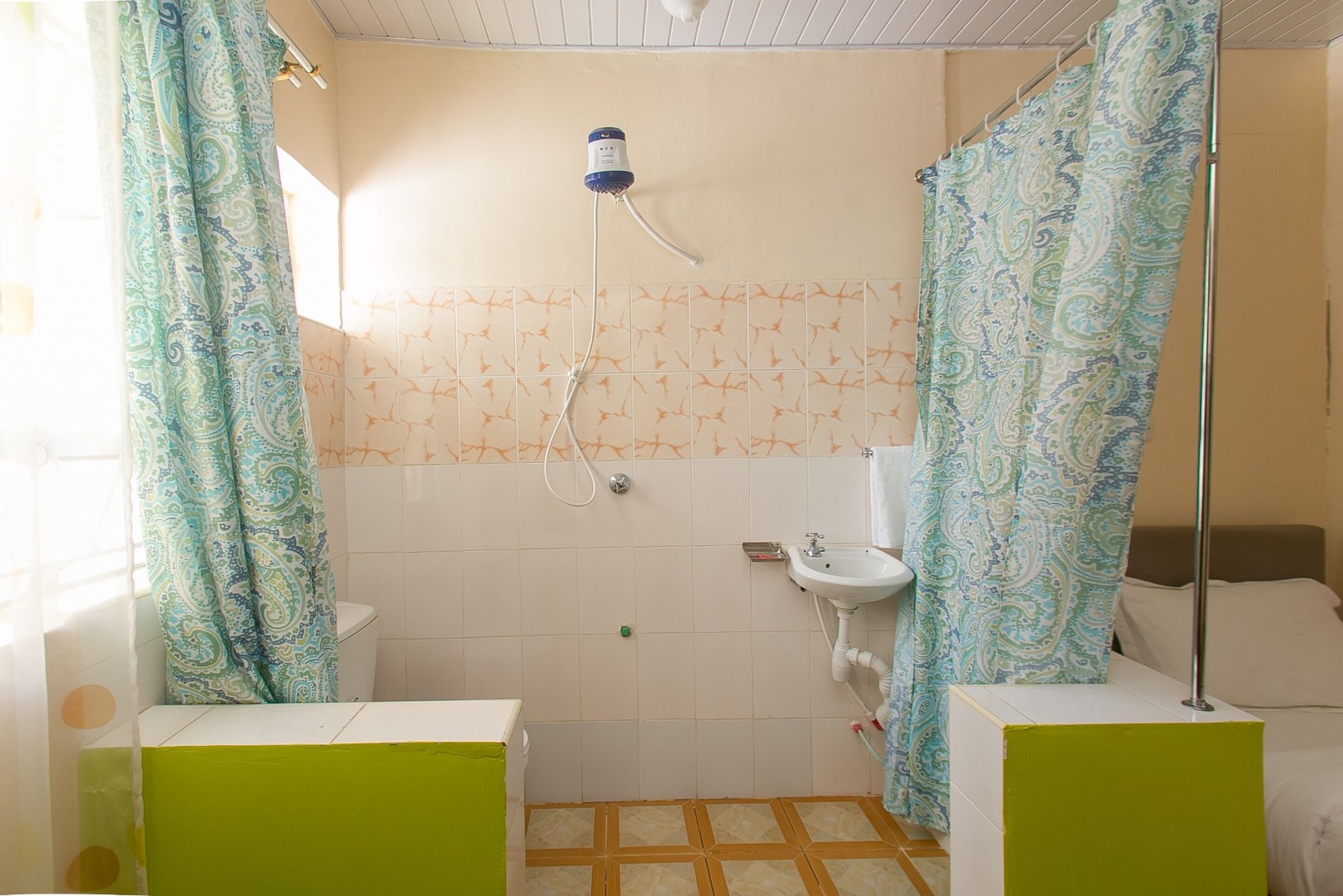 A bathroom with a shower, toilet, sink, and green cabinets.