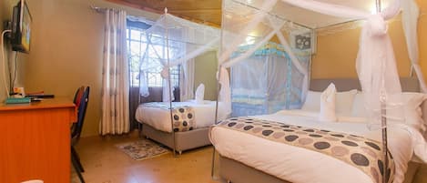 A room with two beds, each with a canopy, a desk, and a chair.
