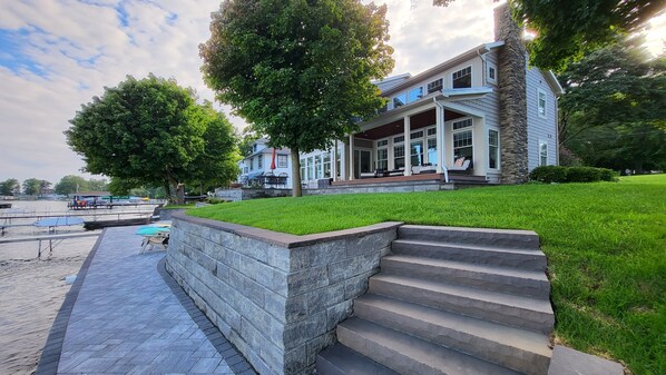 A waterfront property with a stone retaining wall, steps leading to a porch, and a view of the water.