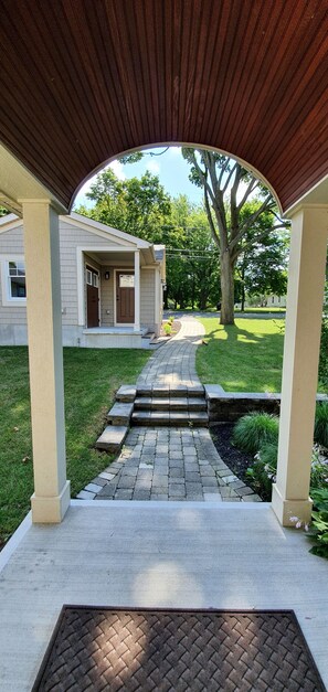 A covered walkway leading to a house with a front door and steps.