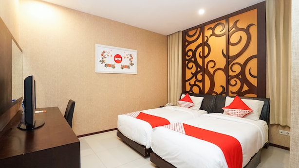 A hotel room with a bed, a desk, and a television. - Oyo 1449 Istana Permata Dinoyo (Surabaya)
