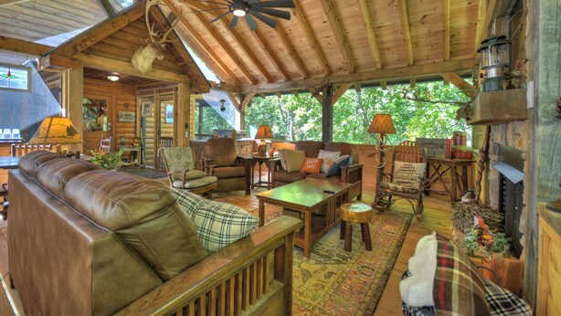 A cozy cabin interior with a wooden ceiling, leather sofa, and rustic decor.