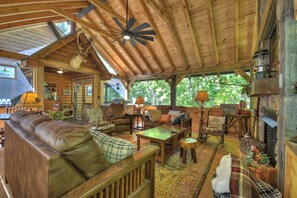 Ein gemütliches Blockhaus-Interieur mit Holzbalkendecke, Ledersofa und rustikalen Einrichtungsgegenständen.