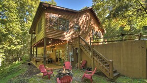 A log cabin with a porch, outdoor seating, and a fire pit.