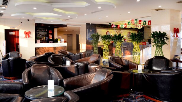 Een hotel lobby met lederen zitplaatsen, een receptiebalie en decoratieve planten.