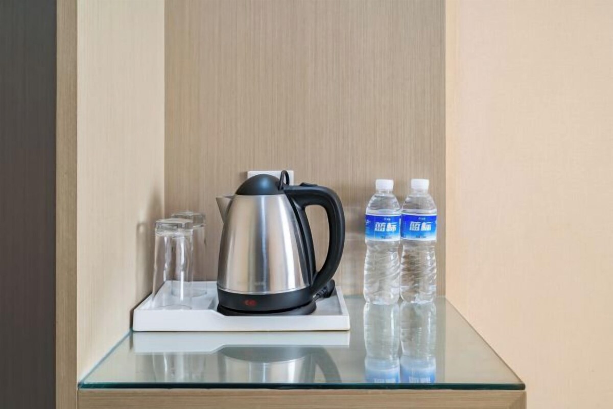 Ein Tisch mit Glasplatte, einer Edelstahl-Wasserkocher, zwei Wasserflaschen und zwei Gläsern.