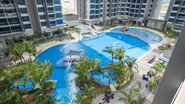 Una amplia piscina interior con varias secciones, rodeada de palmeras y zonas de descanso.