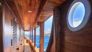Une terrasse en bois dotée d’une fenêtre circulaire et offrant une vue sur la mer.