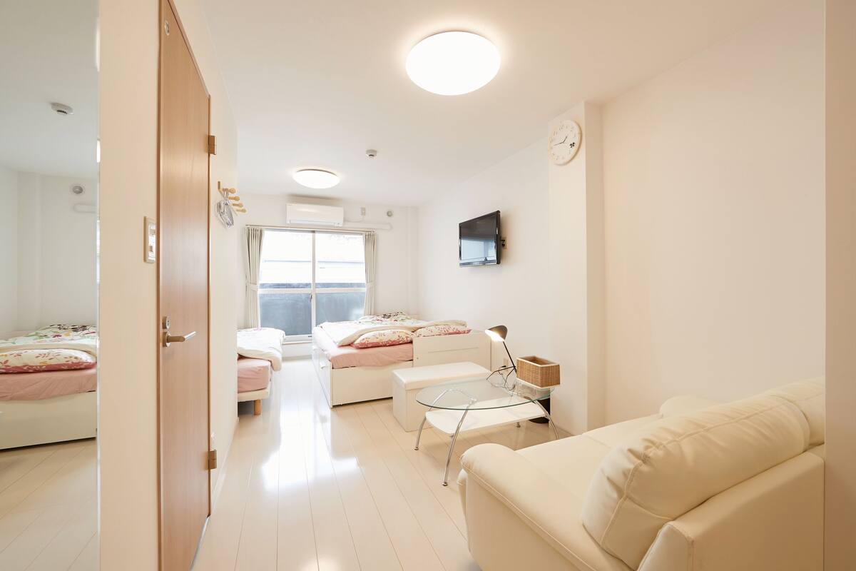 A modern, well-lit bedroom with a bed, bedside table, and a small seating area with a couch.