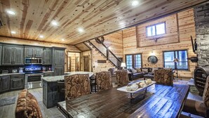 A spacious log cabin interior with a kitchen, dining area, and living room. - Cowboy Castle - Ridge Line Lodge, Hot Tub, Games, Outdoor Entertaining🔥 🌲 (Broken Bow)