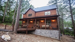 A log cabin with a stone foundation, a porch with seating, and a metal roof. - Cowboy Castle - Ridge Line Lodge, Hot Tub, Games, Outdoor Entertaining🔥 🌲 (Broken Bow)