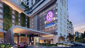 Ett modernt hotell med en tydlig logotyp i form av bokstaven ”R”, en överbyggd entré och en vackert anlagd uppfart.
