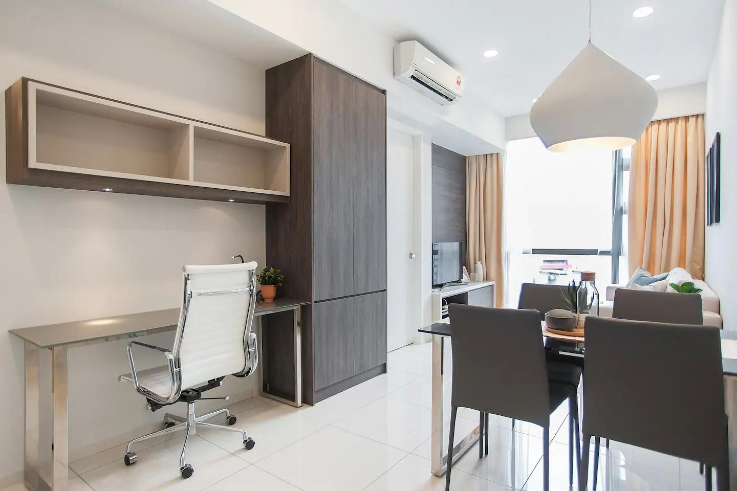 A modern hotel room with a dining area, a white office chair, a desk, a TV, and a large window with curtains.