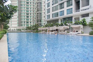 A swimming pool with lounge chairs and umbrellas, surrounded by greenery and modern buildings. - R2 LOVELY 1BR - 5min Bukit Bintang - Pavilion KL (Kuala Lumpur)