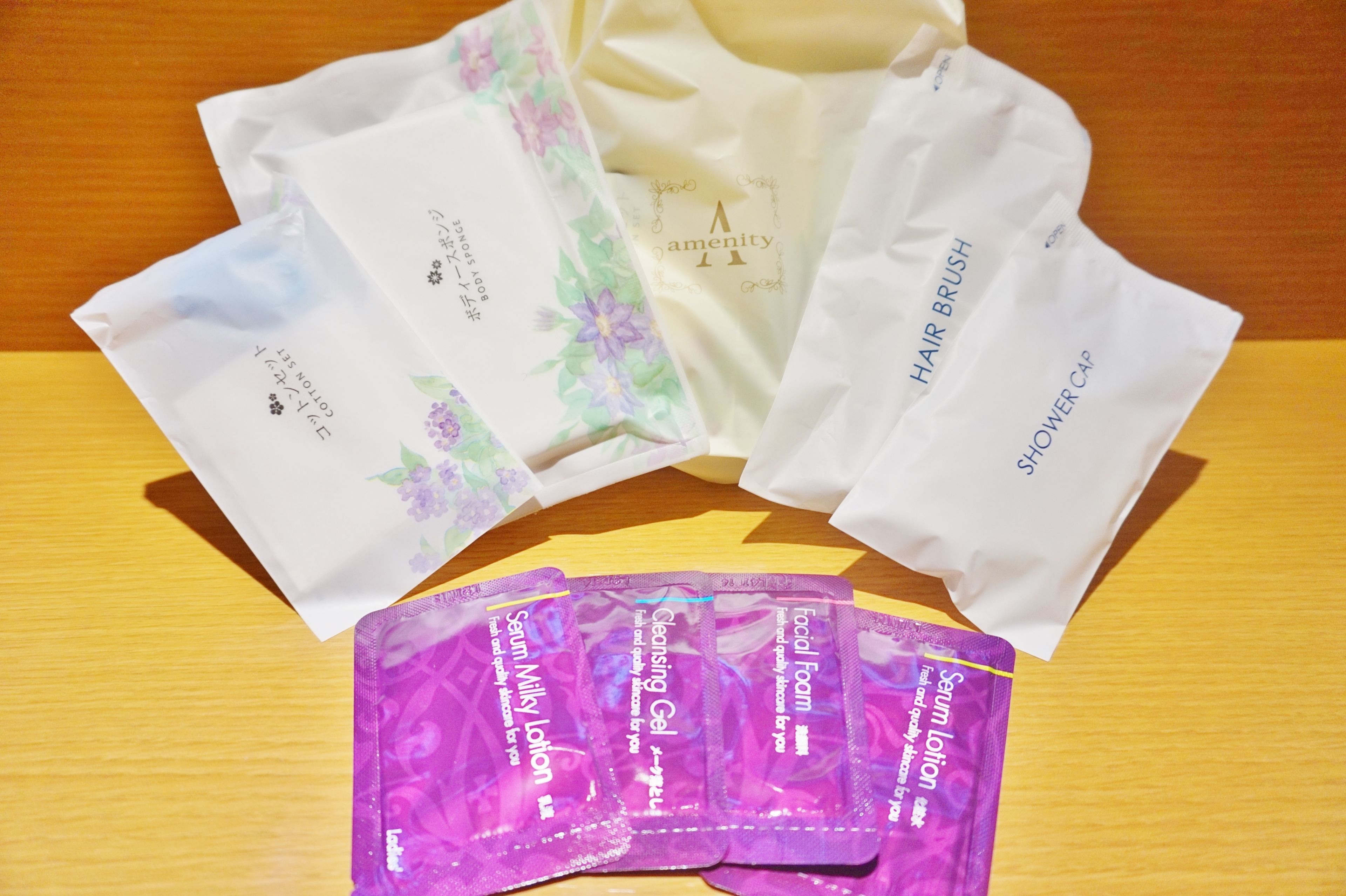 En träyta med olika produkter för personlig hygien, inklusive en hårborste, ett duschschampo och flera förpackningar ansiktsrengöring och rengöringsgel.
