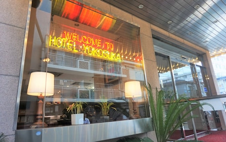 A hotel entrance with a neon sign reading "WELCOME TO HOTEL YOKOSUKA".