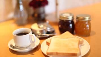 A breakfast setting with a cup of coffee, a plate of toast, and two jars of jam on a wooden table.