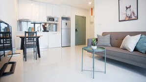 A modern living room with a sofa, a small table, and a dining area with a chair and table. - S8 COZY 1 BR - KLCC - KL Tower - High Speed WiFi (Kuala Lumpur)