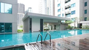 A modern indoor swimming pool with a wooden deck, surrounded by high-rise buildings. - S8 COZY 1 BR - KLCC - KL Tower - High Speed WiFi (Kuala Lumpur)