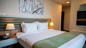 Habitación de hotel con una cama grande, dos lámparas de noche, un teléfono y un cuadro colgado en la pared.