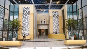 Un vestíbulo moderno con suelo a cuadros, paredes de vidrio y techo con estrellas.