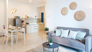 Un soggiorno moderno con un divano grigio, un tavolo da pranzo con sedie, un tavolino da caffè e una cucina sullo sfondo.