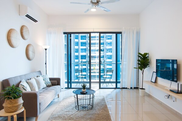 A modern living room with a sofa, a coffee table, a TV, and a large window with a city view.