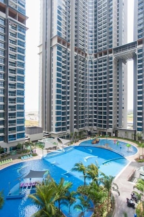 Enjoy a refreshing swim in the central pool surrounded by lush greenery and palm trees.