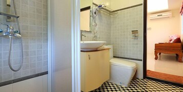 A bathroom with a shower, toilet, sink, and a wooden bench.