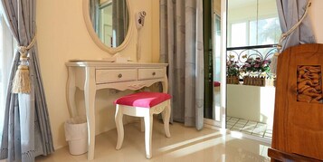 A bathroom with a white vanity, a mirror, a red bench, and a wooden cabinet with a carved design.