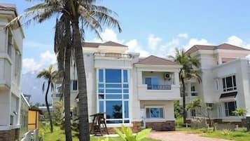 A multi-story residential building with a central courtyard, large windows, and a paved walkway.