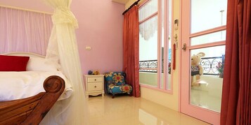 Un dormitorio con cama a dosel, una mesita de noche, una silla colorida y un ventanal con cortinas.