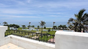A balcony with a metal railing overlooking a grassy area with palm trees and a view of the sea. - Taroko Bay B&B (Xincheng)
