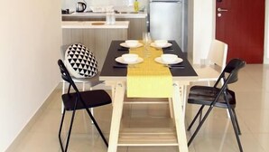 Cozinha moderna com área de refeições, apresentando uma cadeira estampada em preto e branco, uma mesa de madeira e uma luminária pendente.