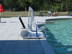 A poolside area with a lounge chair and a sun umbrella.