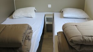Zwei Einzelbetten mit Kopfteilen, kleine Nachttische und eine Wandleuchte.