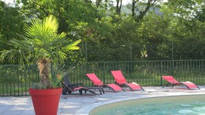 Ein Poolbereich mit einem Topf in Rot, einem Schwimmbecken und roten Liegestühlen.