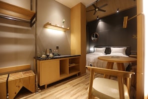 A hotel room with a wooden floor, a bed with white linens, a bedside table with a lamp, a small round table, and a chair. - X-Times Lakeside Hotel (Zhongshan)