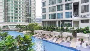 A modern hotel with a swimming pool, outdoor seating areas, and high-rise buildings in the background. - R3 Beautiful 1 BR - Bukit Bintang - Pavilion KL - WIFI (Kuala Lumpur)
