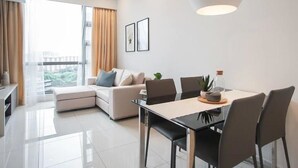 A modern living room with a sofa, dining table, chairs, and a large window with curtains. - R3 Beautiful 1 BR - Bukit Bintang - Pavilion KL - WIFI (Kuala Lumpur)