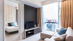 A modern living room with a sofa, a TV on a stand, and a large window with curtains. - R3 Beautiful 1 BR - Bukit Bintang - Pavilion KL - WIFI (Kuala Lumpur)