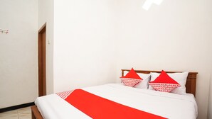 A neatly made bed with a white and red bedspread, two red pillows with white text, and a wooden headboard. - OYO 302 Karolin Homestay (Malang)