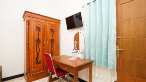 A room with a wooden wardrobe, a red chair, a wooden table, a television mounted on the wall, and a blue curtain. - OYO 302 Karolin Homestay (Malang)
