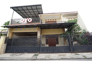A two-story house with a balcony, a gated entrance, and a sign that reads "YO". - OYO 302 Karolin Homestay (Malang)