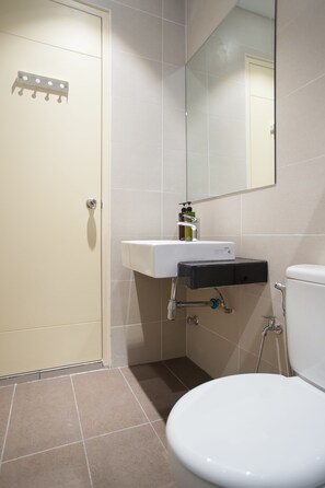 A bathroom with a toilet, a sink, a mirror, and a shower.