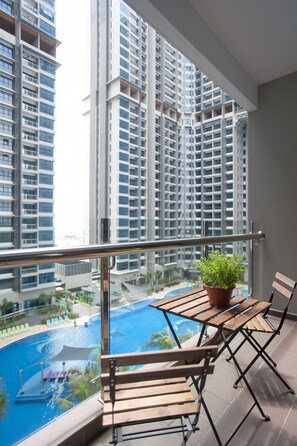 A balcony with a view of a swimming pool and high-rise buildings.