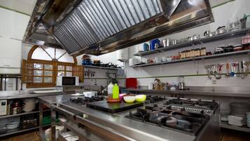 A kitchen with stainless steel appliances, a microwave, and various utensils on shelves.
