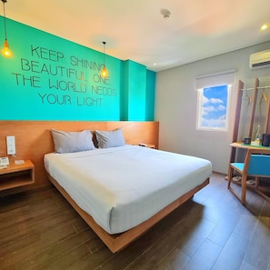 A hotel room with a bed, a nightstand, a mirror, and a motivational wall quote.