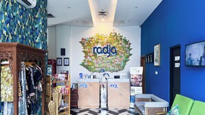 Et receptionsområde med et 'radja hotel'-skilt, en receptionsdisk, en grøn sofa og en væg med et mønster.